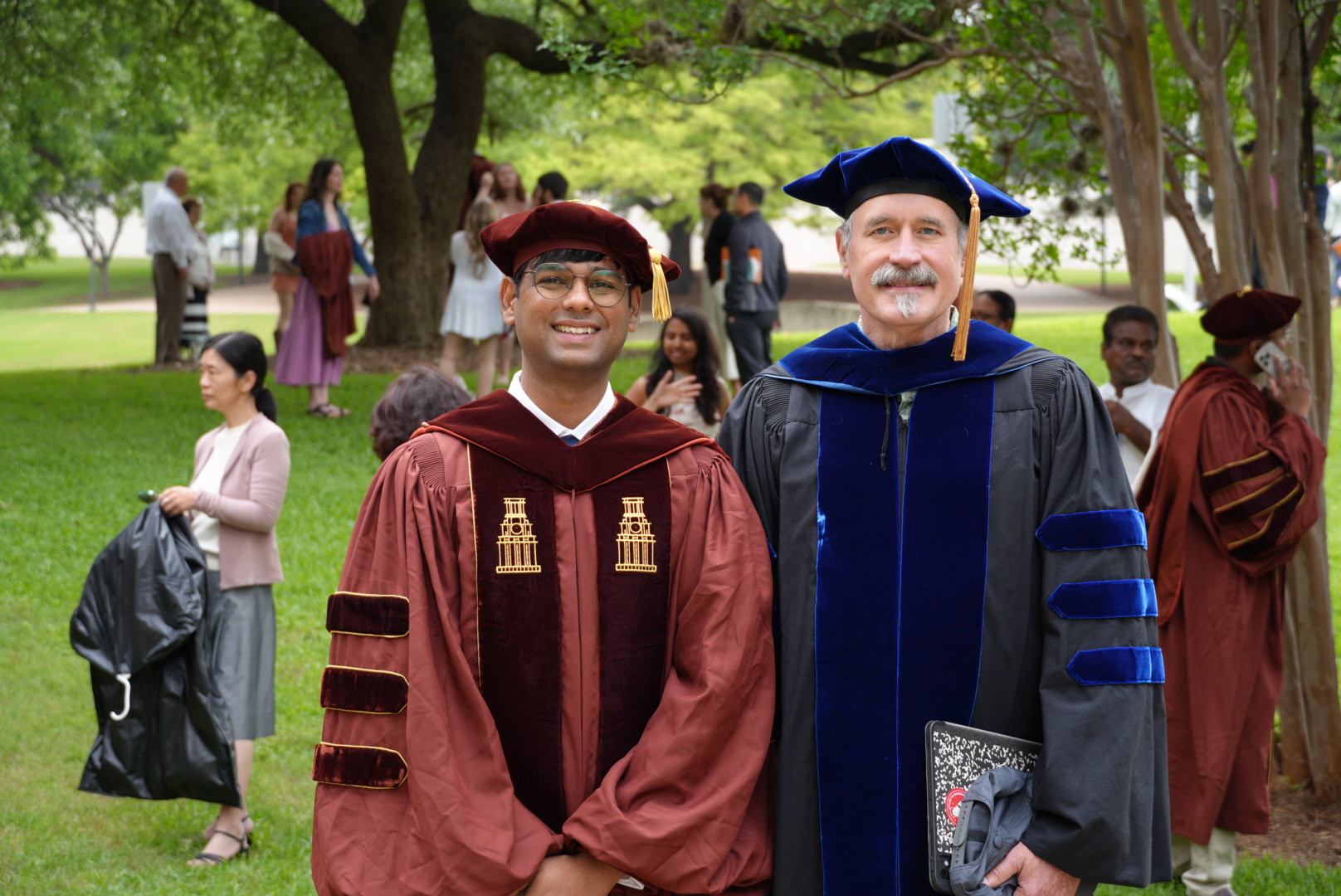 Professor Bovik and me in graduation robes, photographed together under the trees on campus.